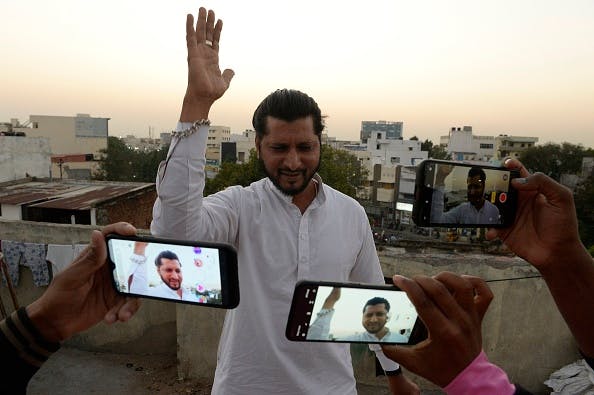 An artist acts in front of a mobile phone camera while making a TikTok video on the terrace of his residence in Hyderabad on February 14, 2020 (NOAH SEELAM / AFP via Getty Images)