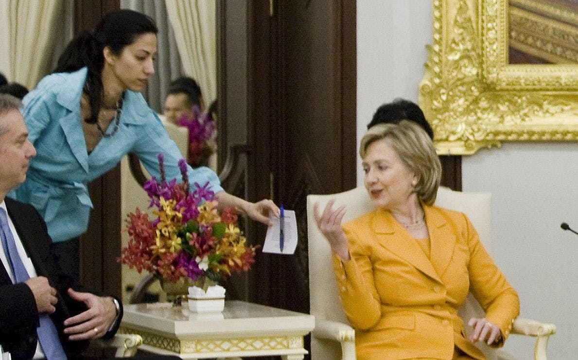 Huma Abedin handing Hillary Clinton notes and a pen (Wikimedia)