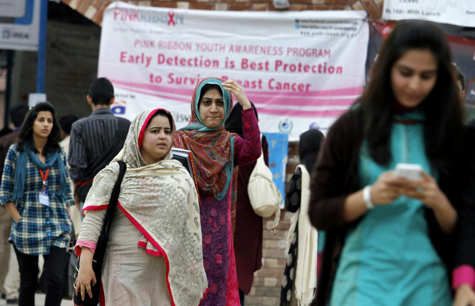 Students walk past a banner promoting awareness on breast cancer at a university in Islamabad, Pakistan. (AP Photo/Anjum Naveed)